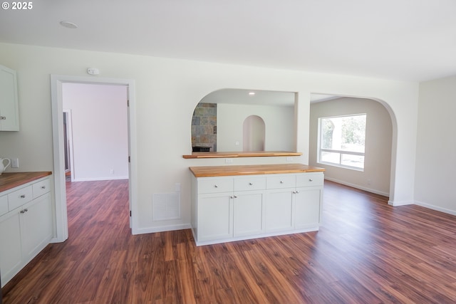 28788 Gimpl Hill Rd, Eugene, OR 97402 - kitchen with butcher block countertops, white cabinets, dark wood-style floors, baseboards, and arched walkways