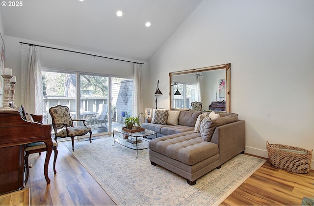 living room with high vaulted ceiling, recessed lighting, wood finished floors, and baseboards