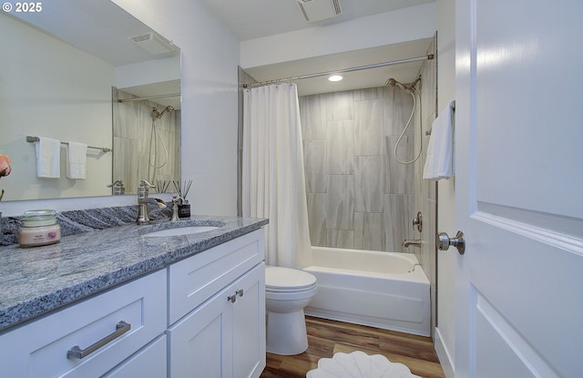 full bath featuring visible vents, toilet, shower / bath combo with shower curtain, vanity, and wood finished floors