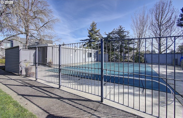 view of gate featuring a patio area, fence, and a fenced in pool