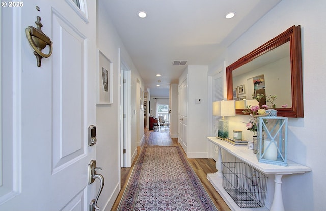 hallway featuring recessed lighting, visible vents, baseboards, and wood finished floors