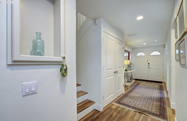 entrance foyer featuring baseboards, visible vents, stairway, wood finished floors, and recessed lighting