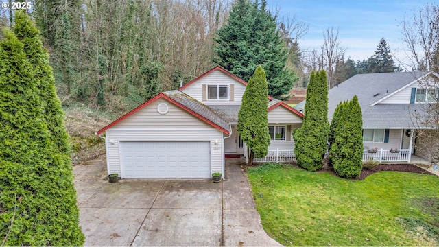 traditional home with a front yard, a porch, an attached garage, a shingled roof, and concrete driveway