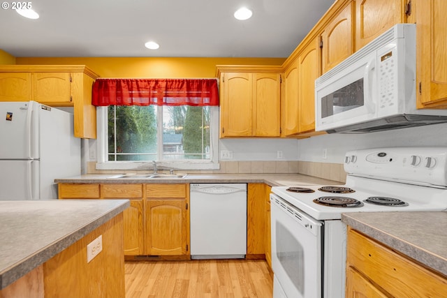 kitchen with light countertops, recessed lighting, light wood-style floors, white appliances, and a sink