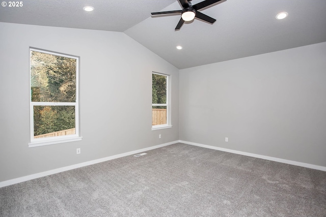 carpeted spare room featuring vaulted ceiling, a textured ceiling, and ceiling fan