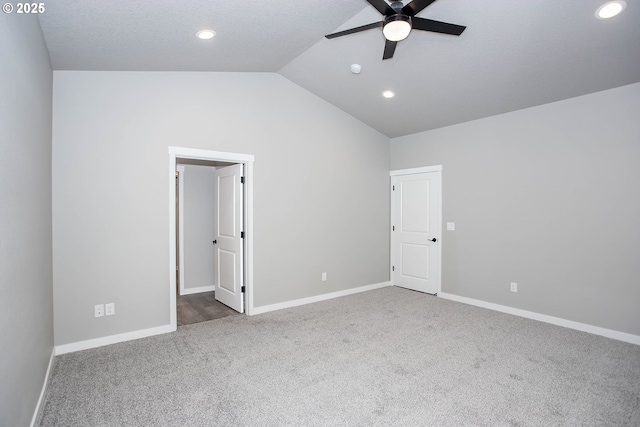 unfurnished bedroom with ceiling fan, a walk in closet, lofted ceiling, and carpet