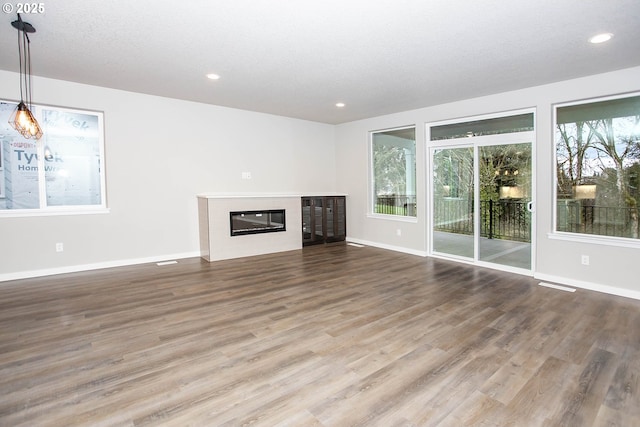 unfurnished living room with hardwood / wood-style floors, a textured ceiling, and a wealth of natural light