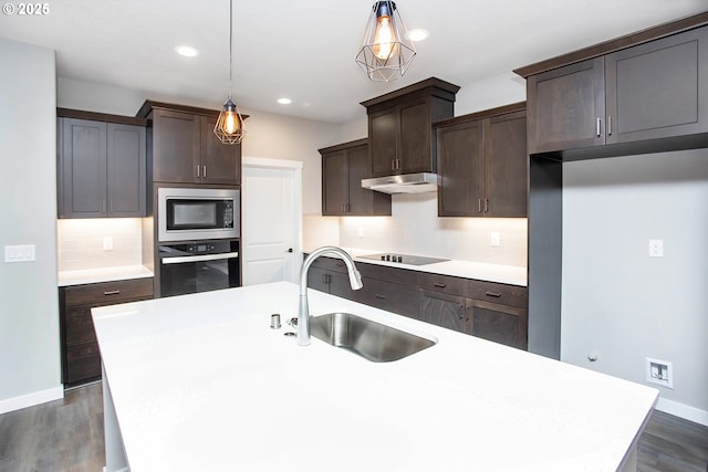 kitchen featuring built in microwave, sink, oven, hanging light fixtures, and black electric stovetop