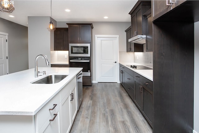 kitchen featuring sink, white cabinetry, light wood-type flooring, appliances with stainless steel finishes, and pendant lighting