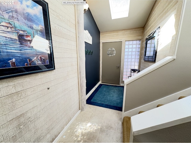 entryway with wooden walls, baseboards, and tile patterned floors