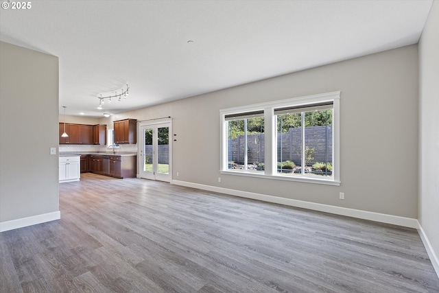 unfurnished living room featuring light wood-type flooring, sink, and track lighting