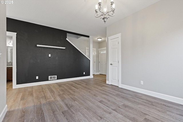 unfurnished living room featuring light wood-type flooring and a chandelier