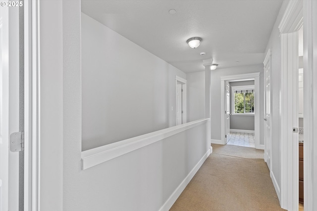 hall featuring light colored carpet and a textured ceiling