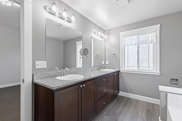 7115 NE Benton Pl, Newport, OR 97365 - full bathroom featuring double vanity, wood finished floors, baseboards, and a tub