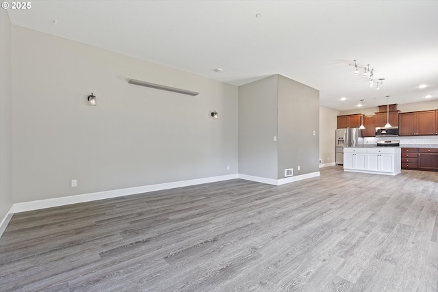 7115 NE Benton Pl, Newport, OR 97365 - unfurnished living room featuring baseboards and light wood-style flooring