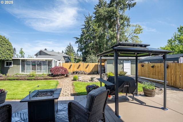 exterior space with a gazebo, a wooden deck, a sunroom, a fenced backyard, and a fire pit
