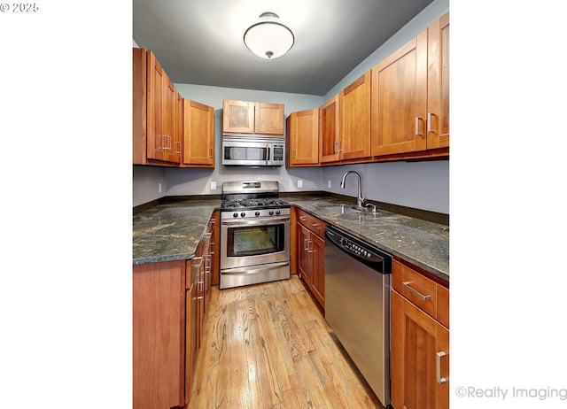 709 SW 16th Ave Unit 105, Portland, OR 97205 - kitchen with stainless steel appliances, a sink, light wood-style flooring, and brown cabinets