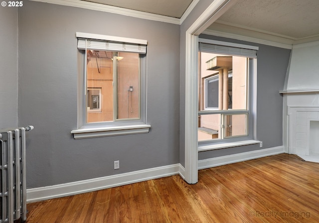 709 SW 16th Ave Unit 105, Portland, OR 97205 - spare room with radiator heating unit, baseboards, wood finished floors, and ornamental molding