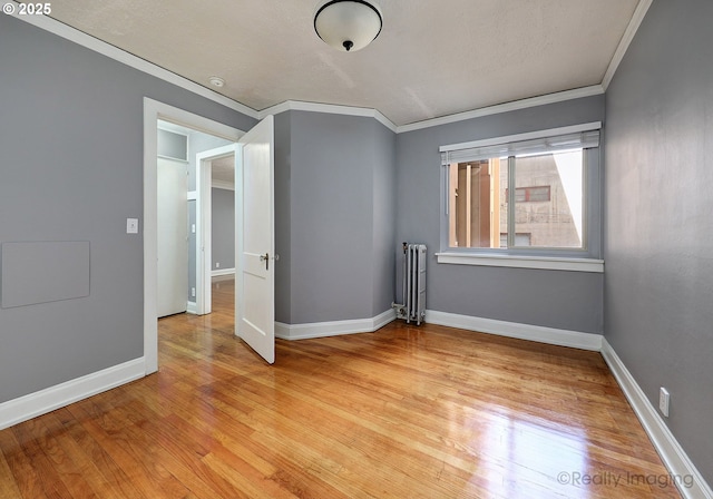 709 SW 16th Ave Unit 105, Portland, OR 97205 - empty room with crown molding, radiator heating unit, light wood-style flooring, and baseboards