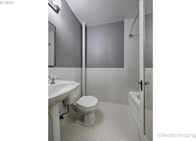 709 SW 16th Ave Unit 105, Portland, OR 97205 - full bathroom featuring toilet, bathtub / shower combination, tile patterned floors, tile walls, and wainscoting