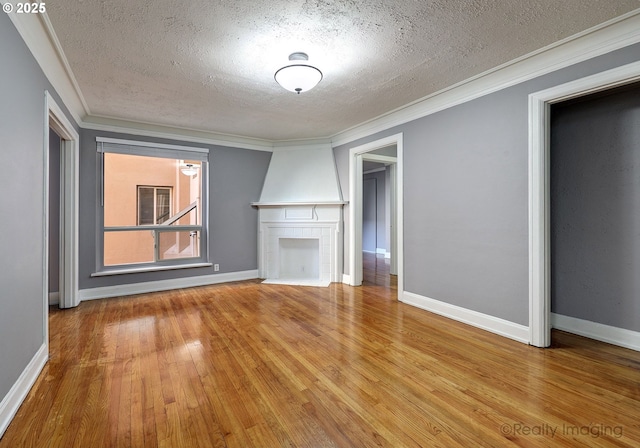 709 SW 16th Ave Unit 105, Portland, OR 97205 - unfurnished living room with a textured ceiling, wood finished floors, a tiled fireplace, ornamental molding, and baseboards
