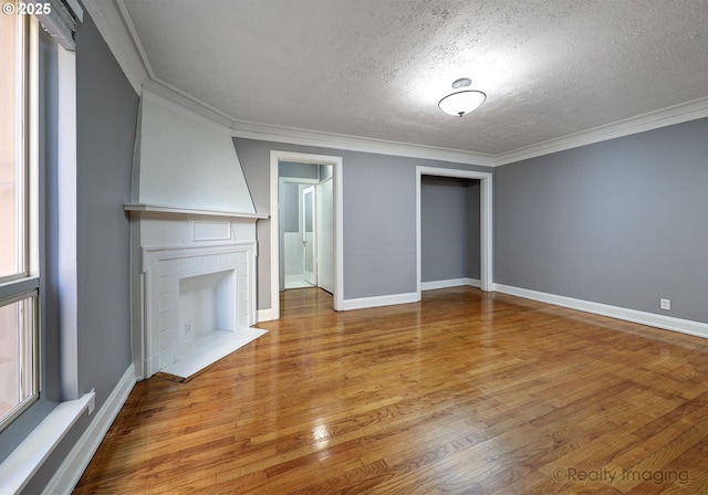 709 SW 16th Ave Unit 105, Portland, OR 97205 - unfurnished living room with wood finished floors, a textured ceiling, baseboards, crown molding, and plenty of natural light