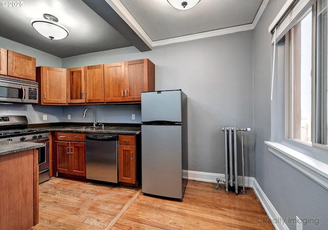 709 SW 16th Ave Unit 105, Portland, OR 97205 - kitchen with appliances with stainless steel finishes, radiator, light wood-style flooring, a sink, and brown cabinetry