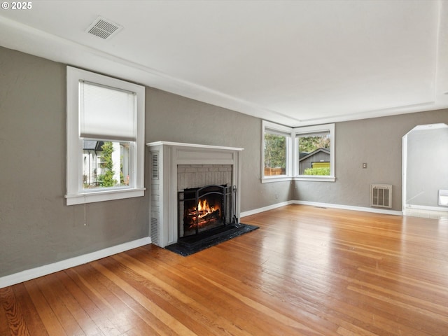 8978 SW Terreton Pl, Portland, OR 97223 - unfurnished living room featuring wood-type flooring, a brick fireplace, healthy amount of natural light, and arched walkways