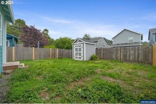 8465 S Hollyhock St, Rockaway Beach, OR 97136 - view of yard with an outbuilding, a fenced backyard, and a storage shed