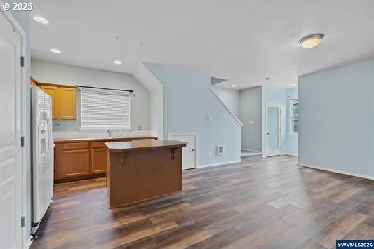 8465 S Hollyhock St, Rockaway Beach, OR 97136 - kitchen with recessed lighting, dark wood-type flooring, white refrigerator with ice dispenser, and a kitchen island
