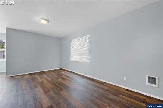 8465 S Hollyhock St, Rockaway Beach, OR 97136 - unfurnished room with wood finished floors, baseboards, visible vents, and plenty of natural light