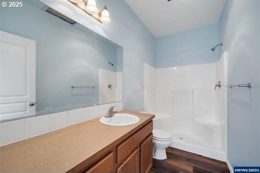 8465 S Hollyhock St, Rockaway Beach, OR 97136 - bathroom with vanity, walk in shower, toilet, and wood finished floors