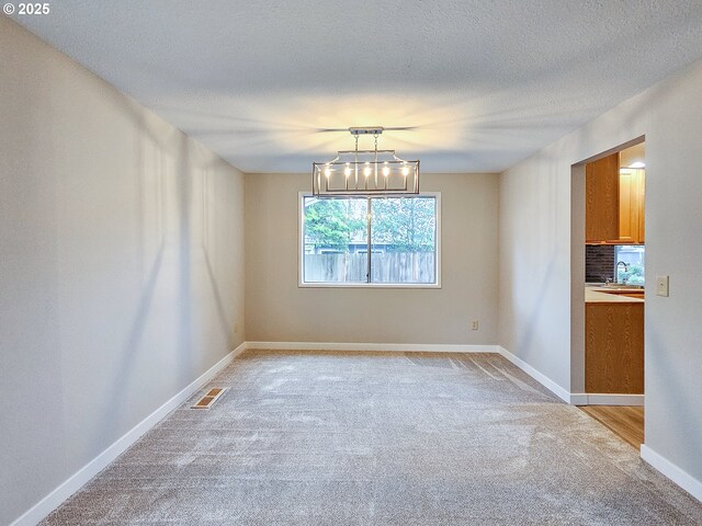 kitchen with a textured ceiling, appliances with stainless steel finishes, and light hardwood / wood-style flooring