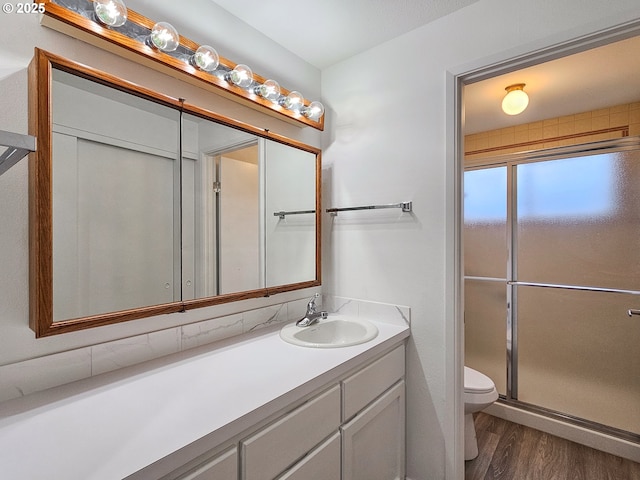 bathroom with hardwood / wood-style flooring, vanity, toilet, and walk in shower