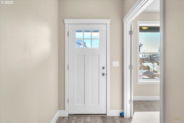 foyer entrance with light wood-style flooring and baseboards