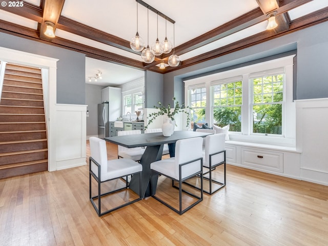 dining space featuring coffered ceiling, a chandelier, stairway, wainscoting, and light wood-type flooring