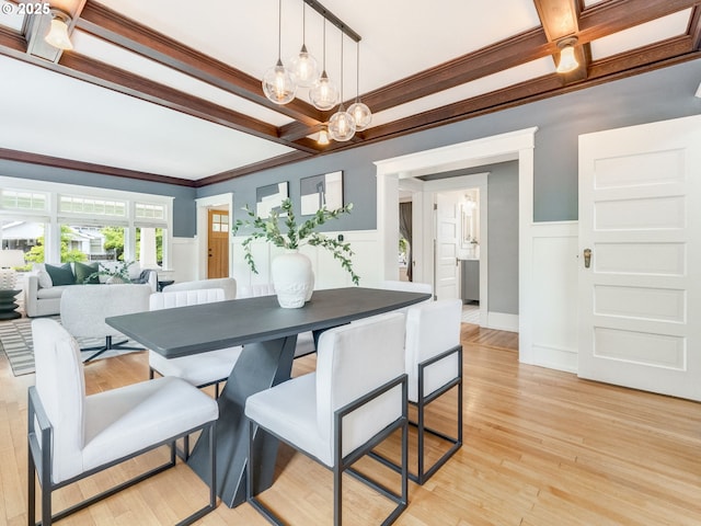 dining room with coffered ceiling, a wainscoted wall, a chandelier, beam ceiling, and light wood finished floors