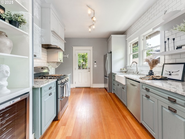 kitchen with stainless steel appliances, beverage cooler, a sink, backsplash, and open shelves