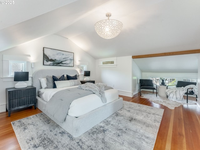 bedroom with vaulted ceiling, wood finished floors, and baseboards