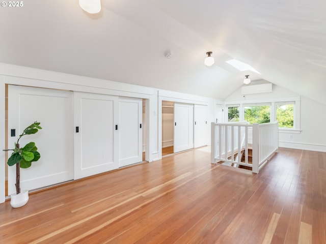 additional living space featuring lofted ceiling, a skylight, and light wood-style floors