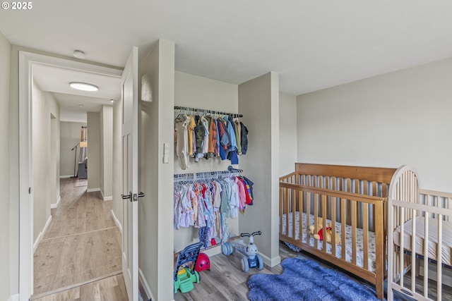 bedroom featuring light wood-type flooring and a nursery area