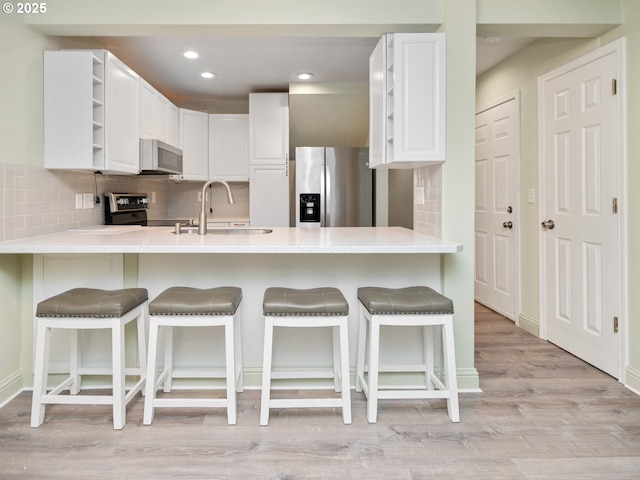 7143 SW Sagert St Unit 105, Tualatin, OR 97062 - kitchen featuring white microwave, stainless steel fridge, open shelves, range, and a peninsula