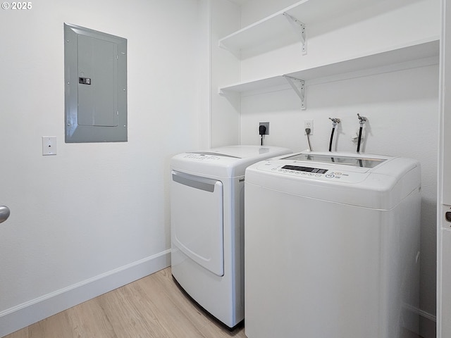 washroom with light wood-style flooring, washer and dryer, laundry area, electric panel, and baseboards