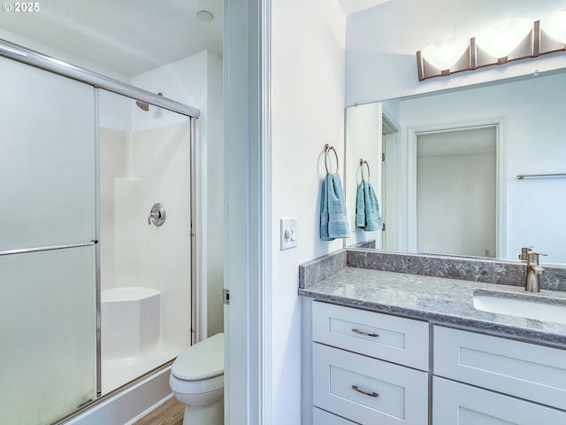 full bath with toilet, a shower stall, wood finished floors, and vanity