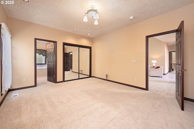 16402 SE Teal Ct, Damascus, OR 97089 - unfurnished bedroom with light carpet, a textured ceiling, baseboards, ensuite bathroom, and a closet