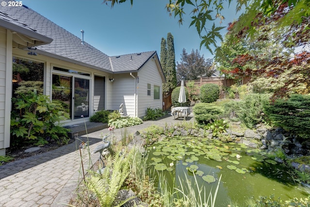 16402 SE Teal Ct, Damascus, OR 97089 - view of side of home with a garden pond, roof with shingles, and a patio area
