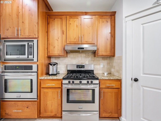 kitchen featuring decorative backsplash, light stone countertops, and appliances with stainless steel finishes