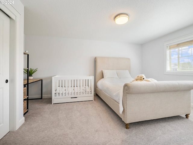 bedroom featuring light colored carpet and a textured ceiling