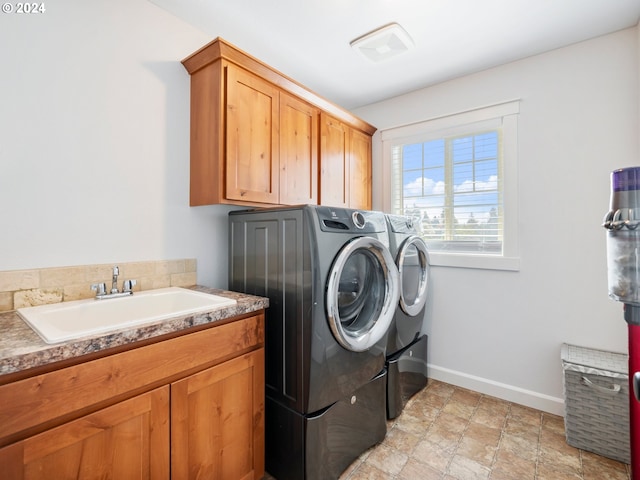 clothes washing area with cabinets, washer and dryer, and sink