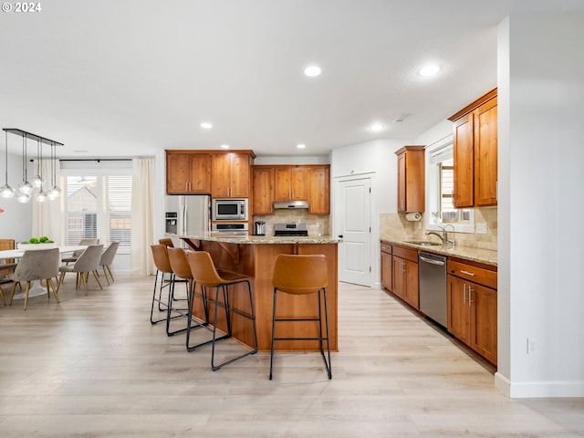 kitchen with appliances with stainless steel finishes, hanging light fixtures, a kitchen island, and backsplash